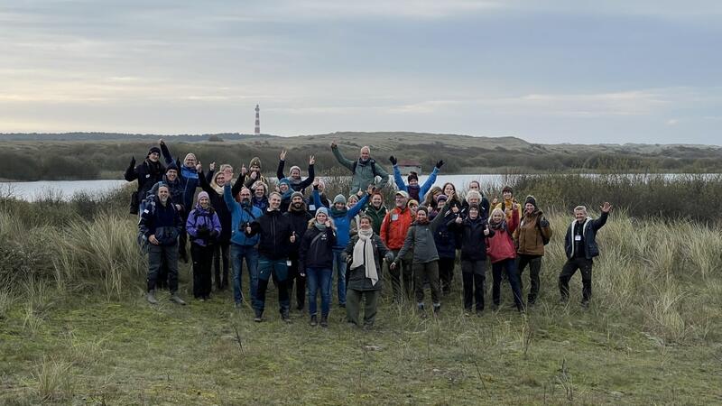 Participants of the 2024 IWSS workshop in the marshes with the Ameland lighthouse in the background. © CWSS/ Bostelmann.